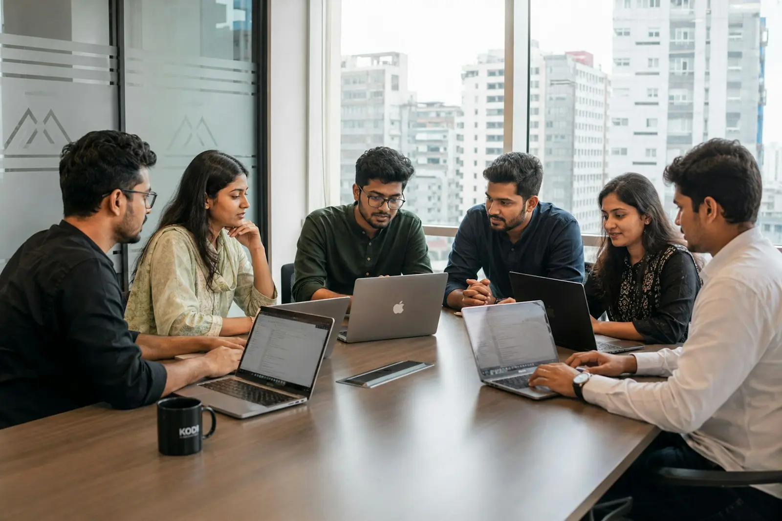 Young team collaborating around a table with laptops
